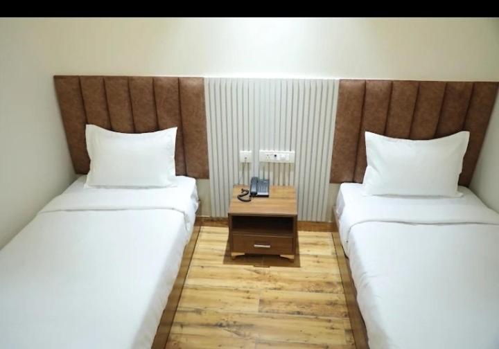 two beds sitting next to each other in a room at La Falcon Hotel in Rohtak
