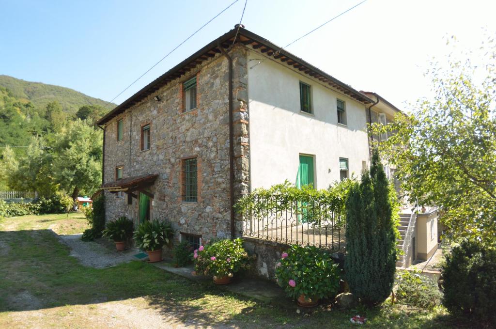 uma antiga casa de pedra com portas verdes e flores em Casale Irene em Pescaglia