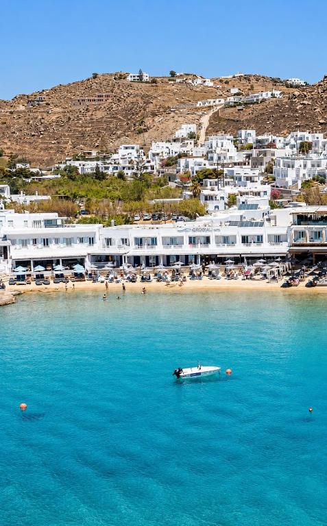 a boat in the water in front of a beach at Acrogiali Beachfront Hotel Mykonos in Platis Gialos