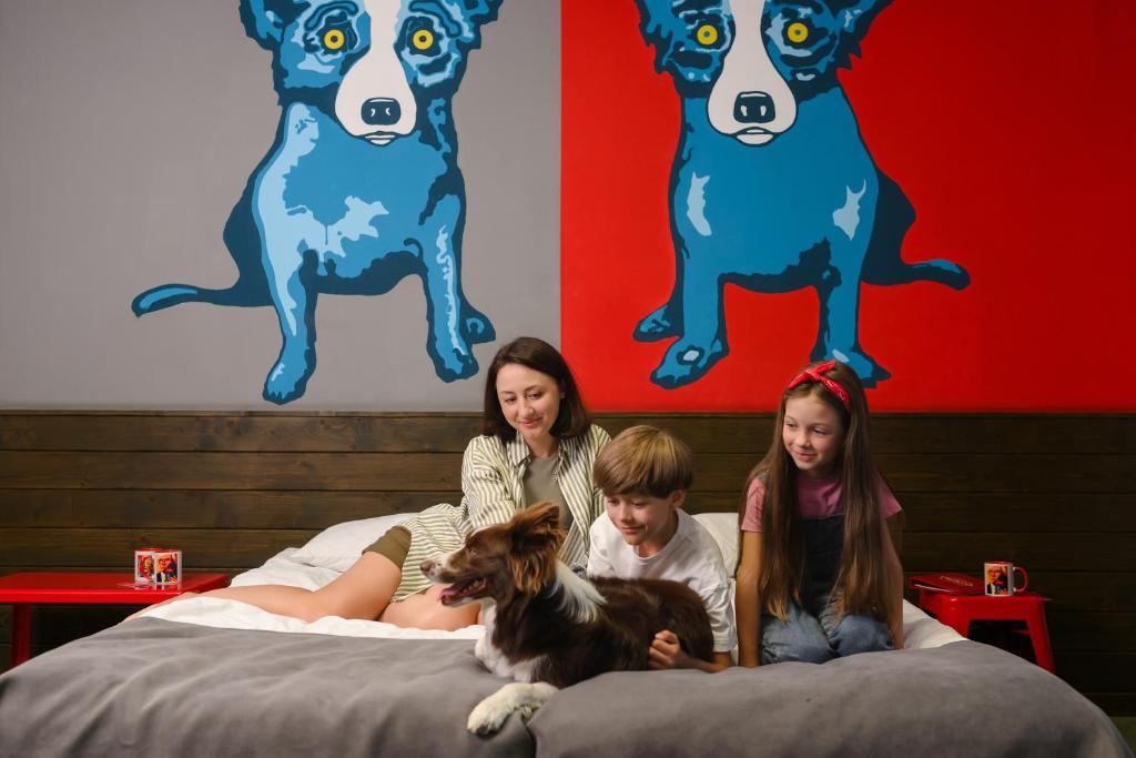 a woman and two children sitting on beds with a dog at Emigrand Art Hotel in Uzhhorod