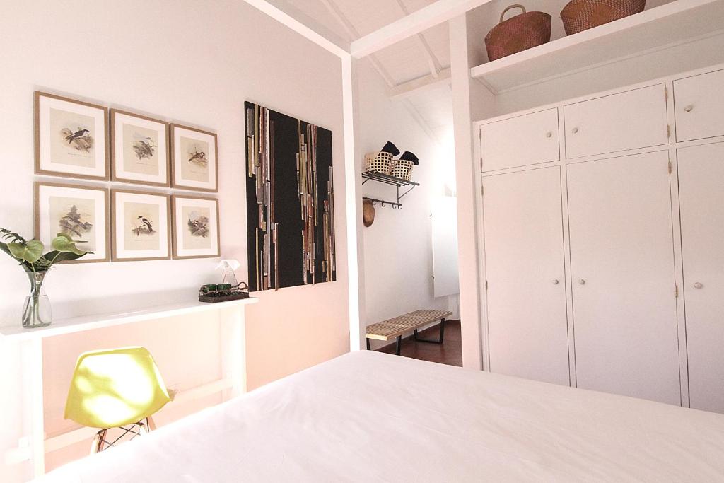 a bedroom with a white bed and a yellow chair at Senhora do Cabo Meco Homy Holidays in Sesimbra