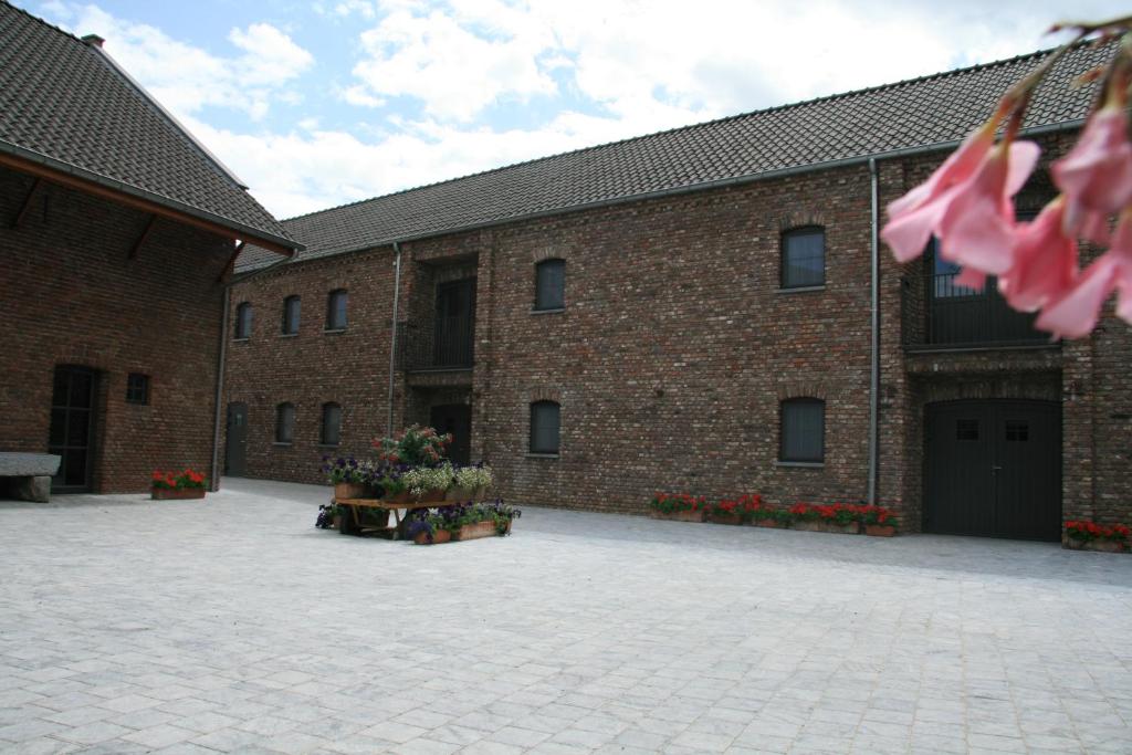 a brick building with a courtyard with flowers in it at Hotel Oude Eycke in Maaseik