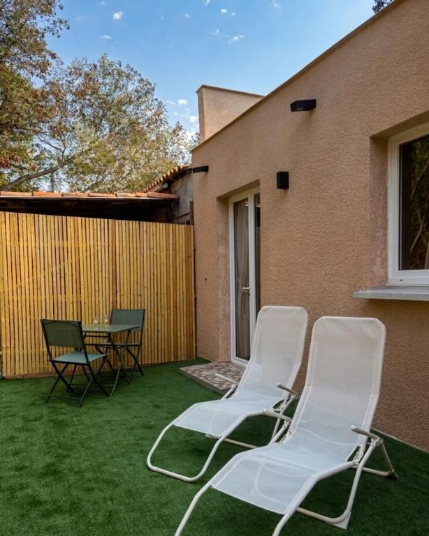 two white chairs and a table on a yard at A Casa Rosa in Omessa