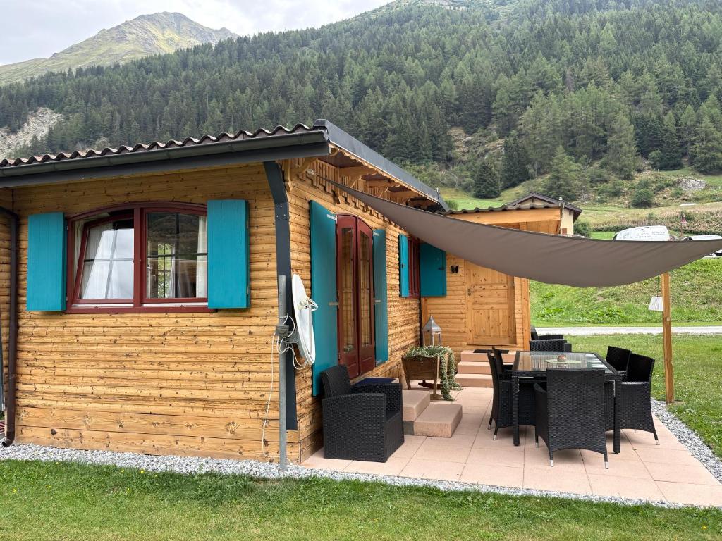 a log cabin with a table and a large umbrella at Mobile home Le paradis dans la nature in Bourg-Saint-Pierre