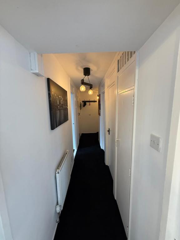 a hallway with a long black floor and white walls at Modern in Orpington