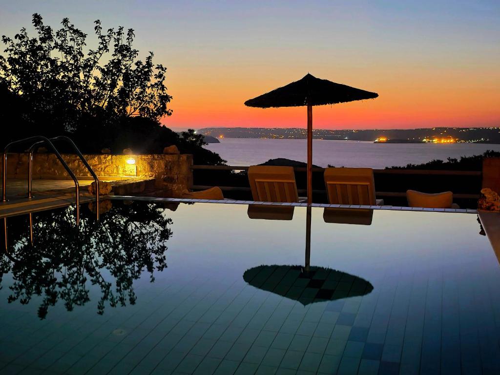 a swimming pool with an umbrella and chairs and water at Bliss House Villa in Plaka