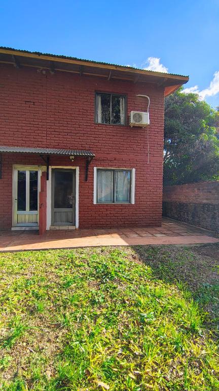 a red brick house with a porch and a yard at Departamento cercano al centro in Oberá