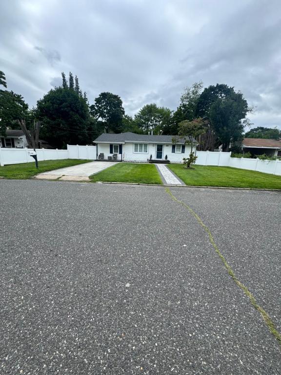 an empty road in front of a white house at Bright & Comfortable Home in the Heart of It All in Central Islip