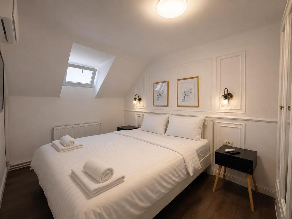 a bedroom with a white bed with two towels on it at Lev Or Aparthotel in Bucharest