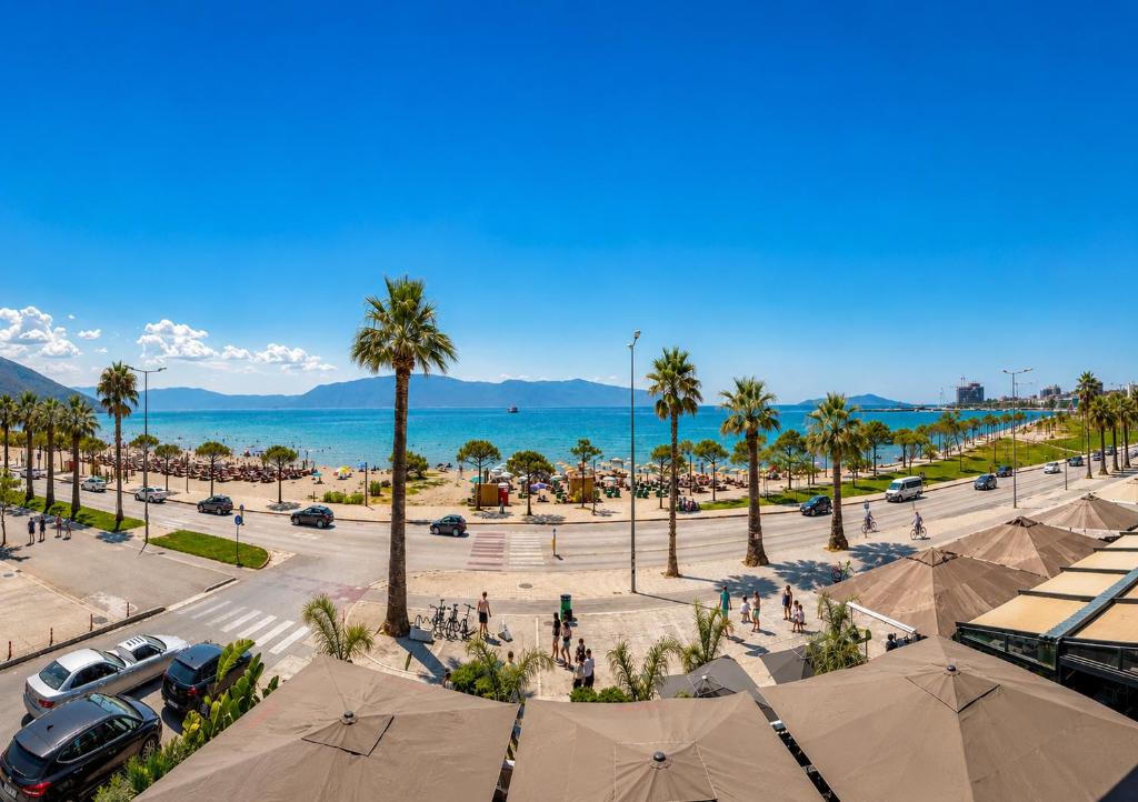 a view of a parking lot with palm trees and the ocean at Hotel Primavera in Vlorë