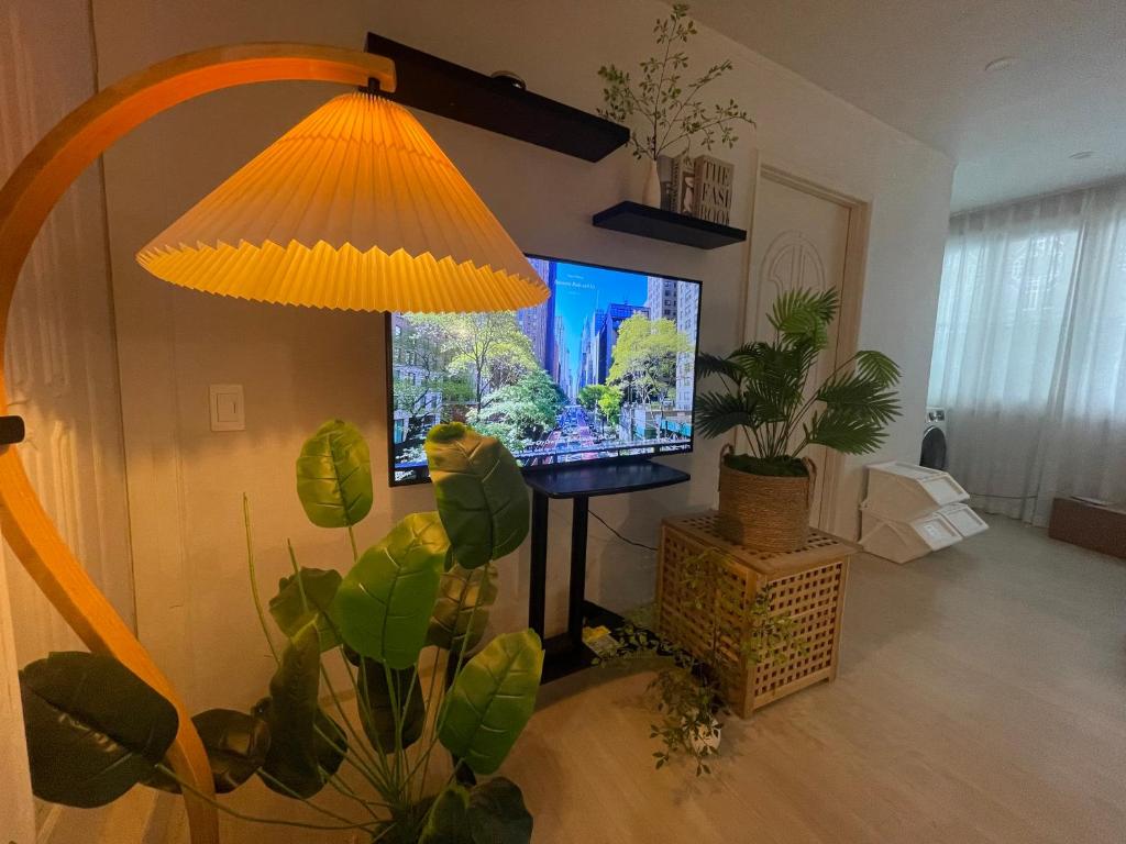 a living room with a television and a lamp at Busan Harbor Stay in Busan