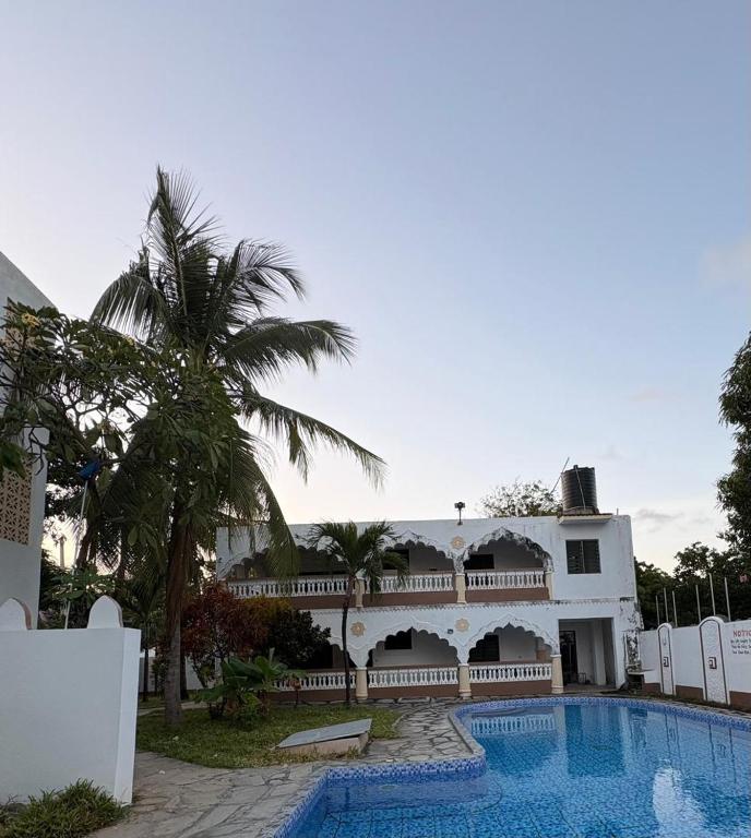 a large white building with a swimming pool and palm trees at Villa Tuffah in Watamu