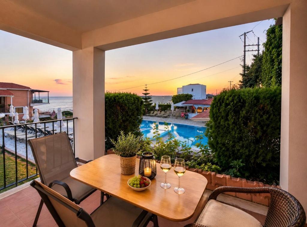 a table with wine glasses on a balcony with a view of the ocean at Aristomenis Studios in Vlachata