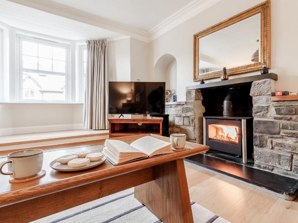 a living room with a fireplace and a table with books at Mill View in Aberfeldy