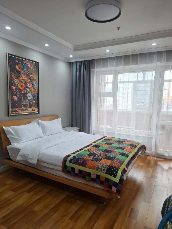 a bedroom with a bed and a painting on the wall at Undraa's cosy small apt in Ulaanbaatar