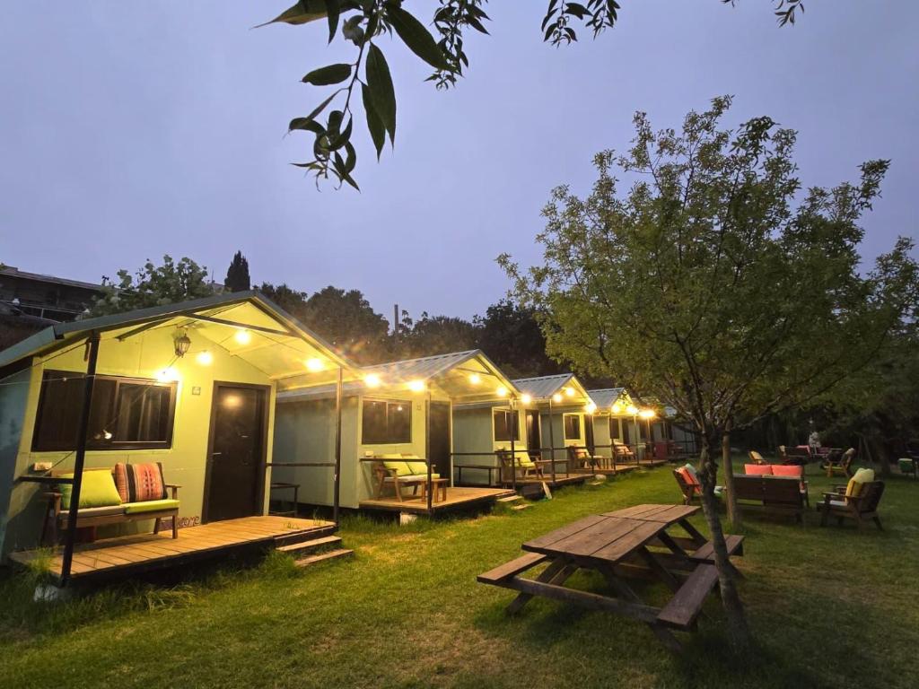 a row of lodges with a picnic table in the grass at מאי טאי ויליג' - 8 בקתות מהממות מול הנוף in Mas'ada