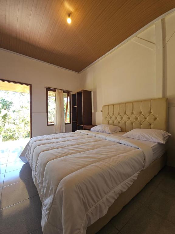 a large bed in a bedroom with a large window at Senaru Garden Homestay in Senaru