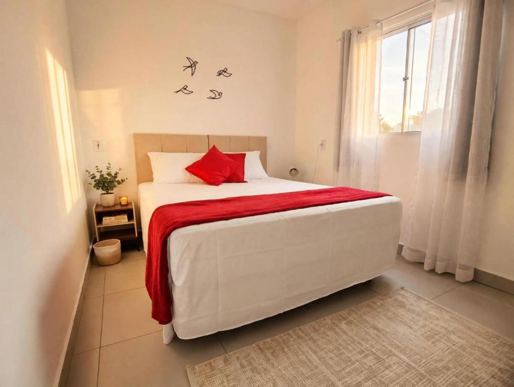 a bedroom with a large white bed with a red blanket at Estúdios VILA 5 Hotel, próximo a Praça dos Três Poderes in Brasília
