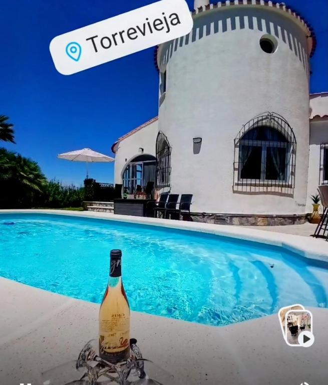 a bottle of wine sitting next to a swimming pool at Casa El Flamenco Zoutmeer Torrevieja 6 of 8 personen in Torrevieja