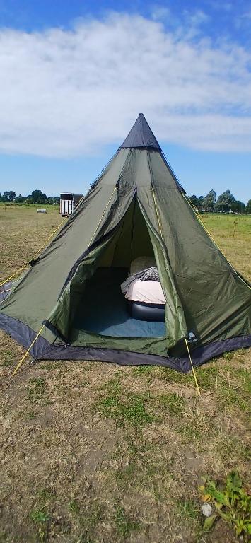 a green tent in the middle of a field at Tipi tent met 2 persoons luchtbed in Sneek