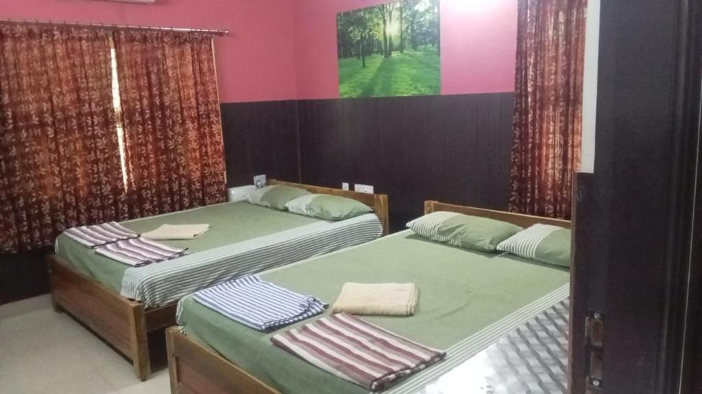 two beds in a room with pink and green at CHIDAMBARAM Bala Residency in Chidambaram