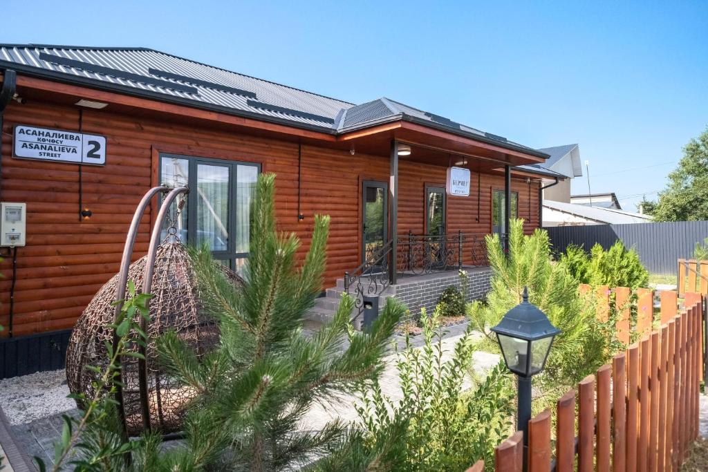 a wooden house with a fence in front of it at Bermet guest house in Karakol