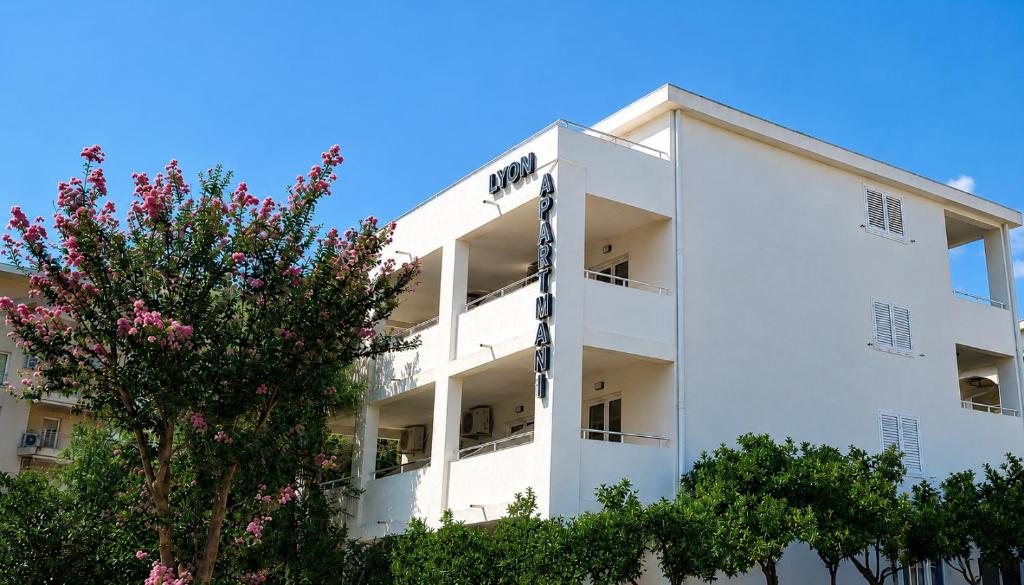 a white building with trees in front of it at Lyon Apartments in Budva