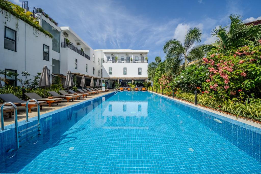 a swimming pool at a hotel with chairs and flowers at Onederz Kampot in Kampot
