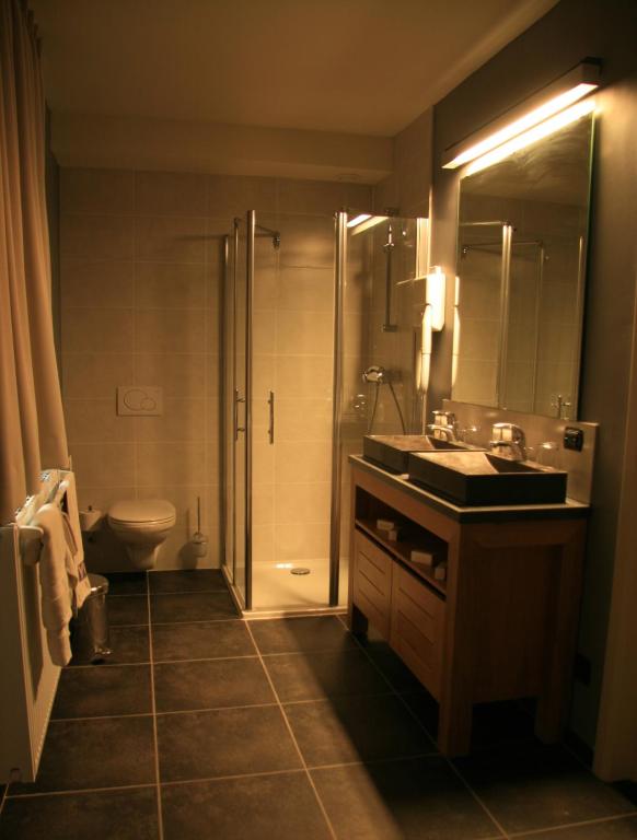 a bathroom with a sink and a shower and a toilet at Hotel Oude Eycke in Maaseik