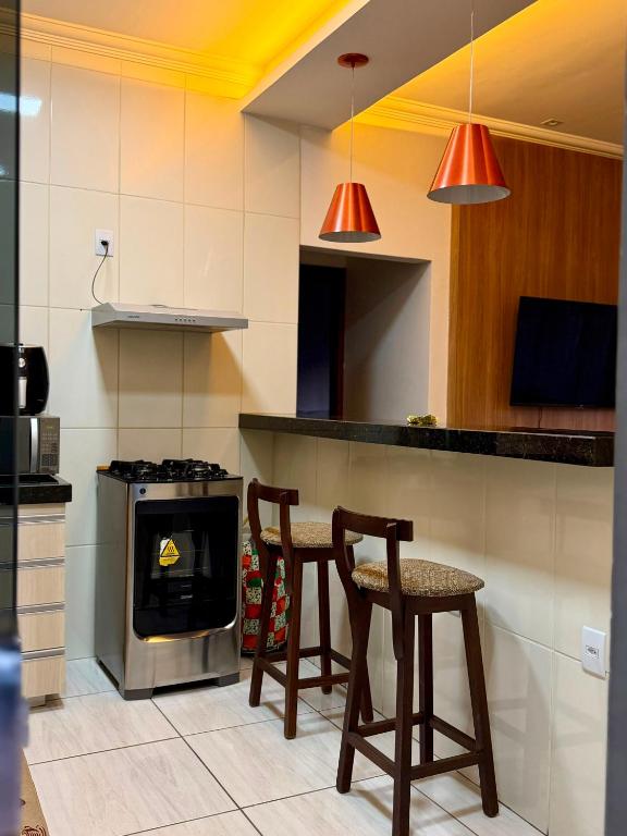 a kitchen with two chairs and a table and a stove at Apartamento Prates - Próx a BR 040 in Sete Lagoas