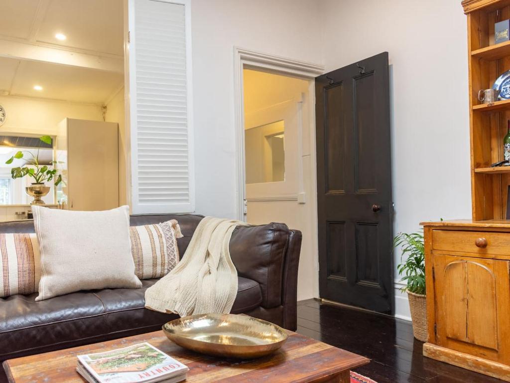 a living room with a leather couch and a table at Secluded Hackney Cottage Near Botanic Gardens with Free Parking - Koala Stay in Adelaide