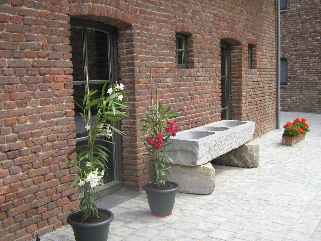 a brick building with a bench and flowers in pots at Hotel Oude Eycke in Maaseik