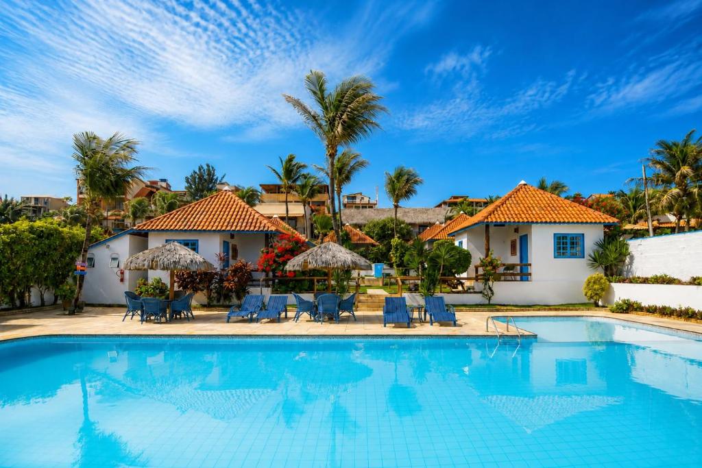 a pool with chairs and umbrellas in front of a house at Pousada Tranquilandia Village in Canoa Quebrada