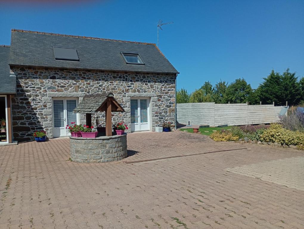 a stone house with a stone fountain in front of it at La maison aux papillons in Tregueux