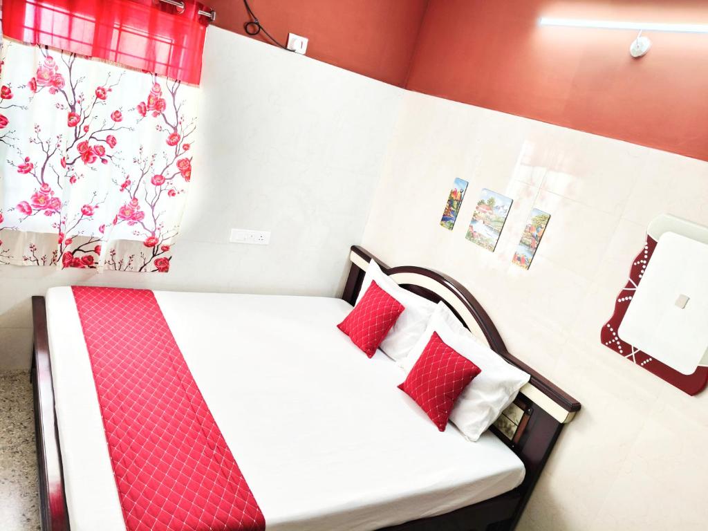 a bedroom with a bed with red and white pillows at Hotel Jyothi Kumar Royal ac rooms in Srikalahasti