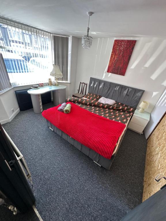 a bedroom with a red bed with a desk and a table at Quiet room Nr 1 in Coventry