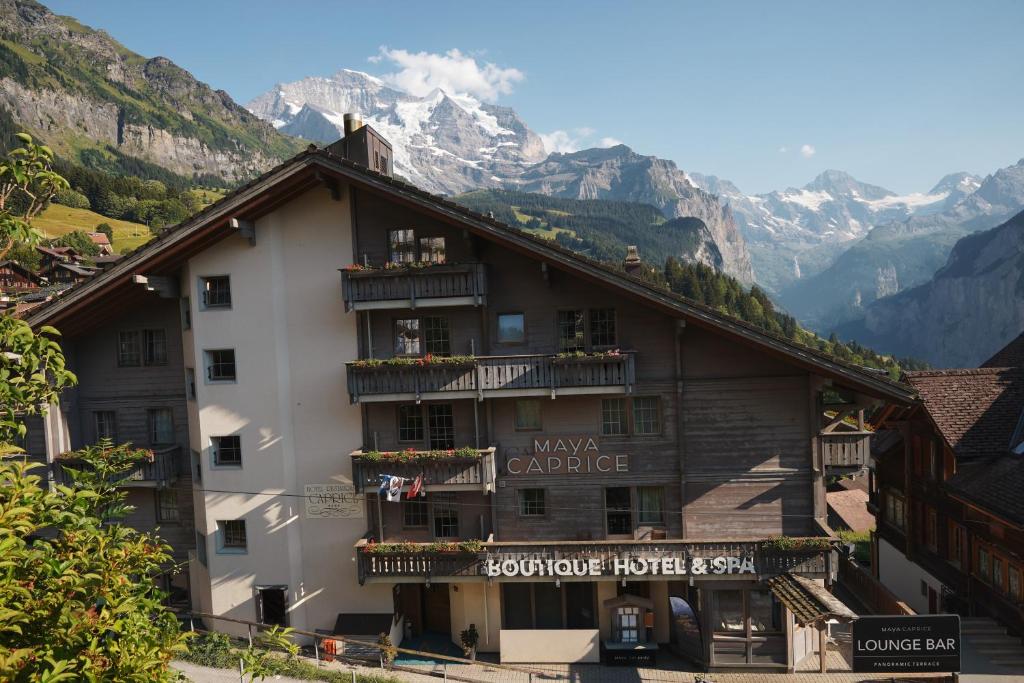 a building with balconies and mountains in the background at Hotel Maya Caprice in Wengen