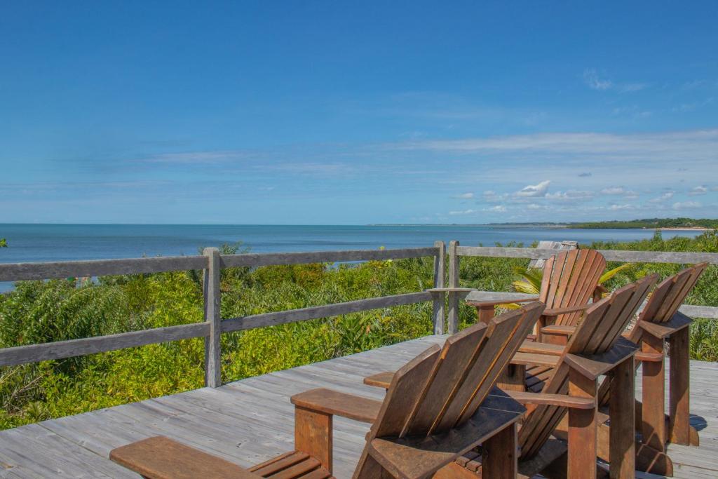 a wooden table and chairs sitting on a deck with the beach at Village Mata Encantada in Santo André