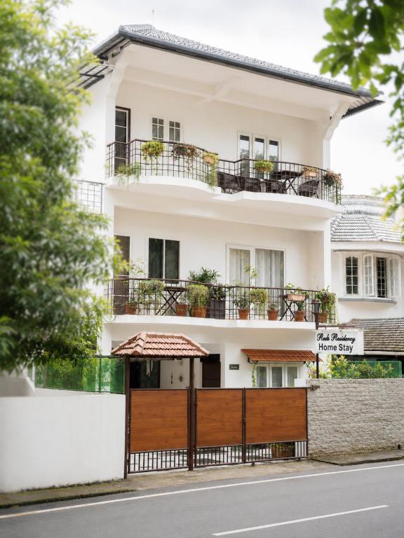 a white building with balconies and a fence at Reds Residency - Homestay in Cochin