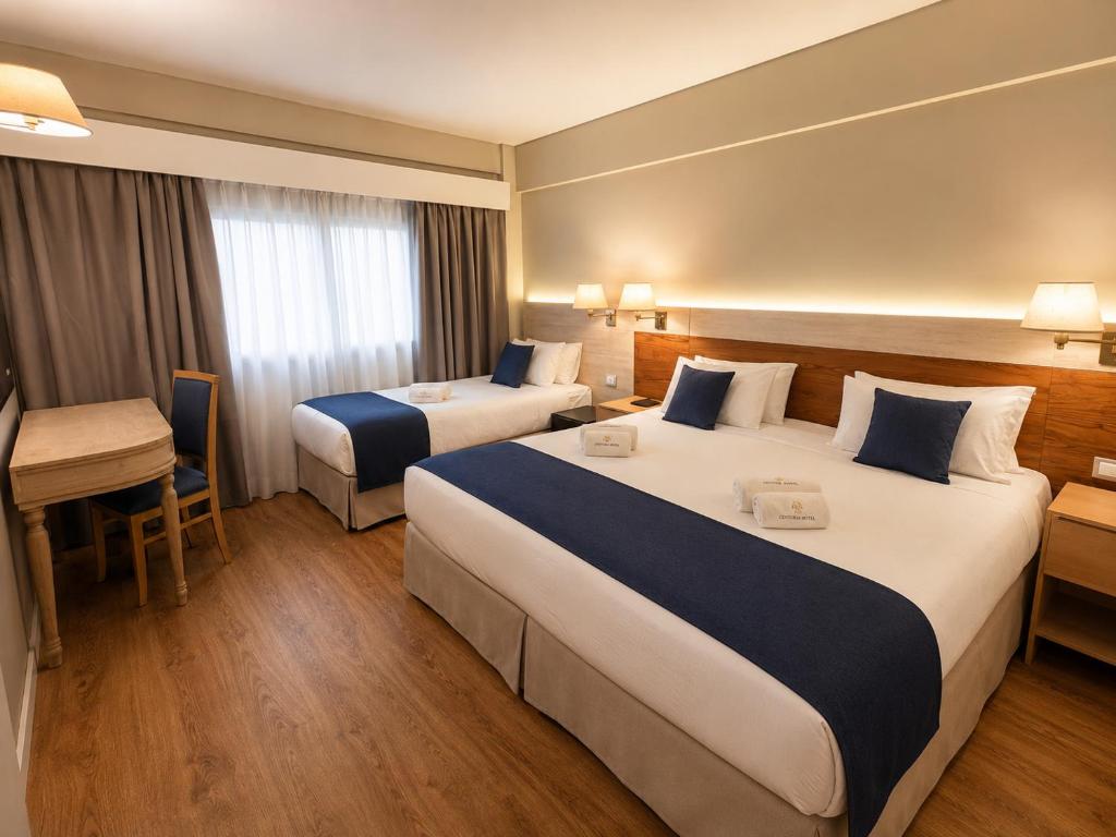 a hotel room with two beds and a desk at Hotel Centuria Obelisco in Buenos Aires