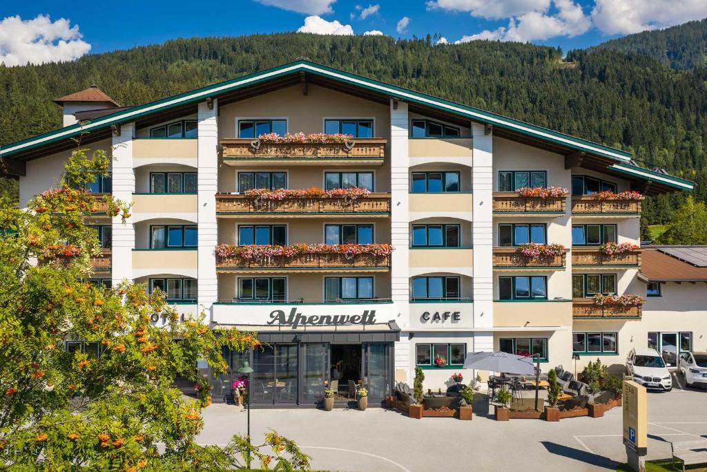 a hotel in a parking lot with a mountain at Hotel Alpenwelt Superior in Flachau