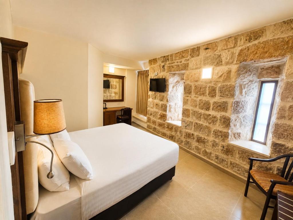 a bedroom with a bed and a stone wall at The Annexe - by Gloria Hotel in Jerusalem