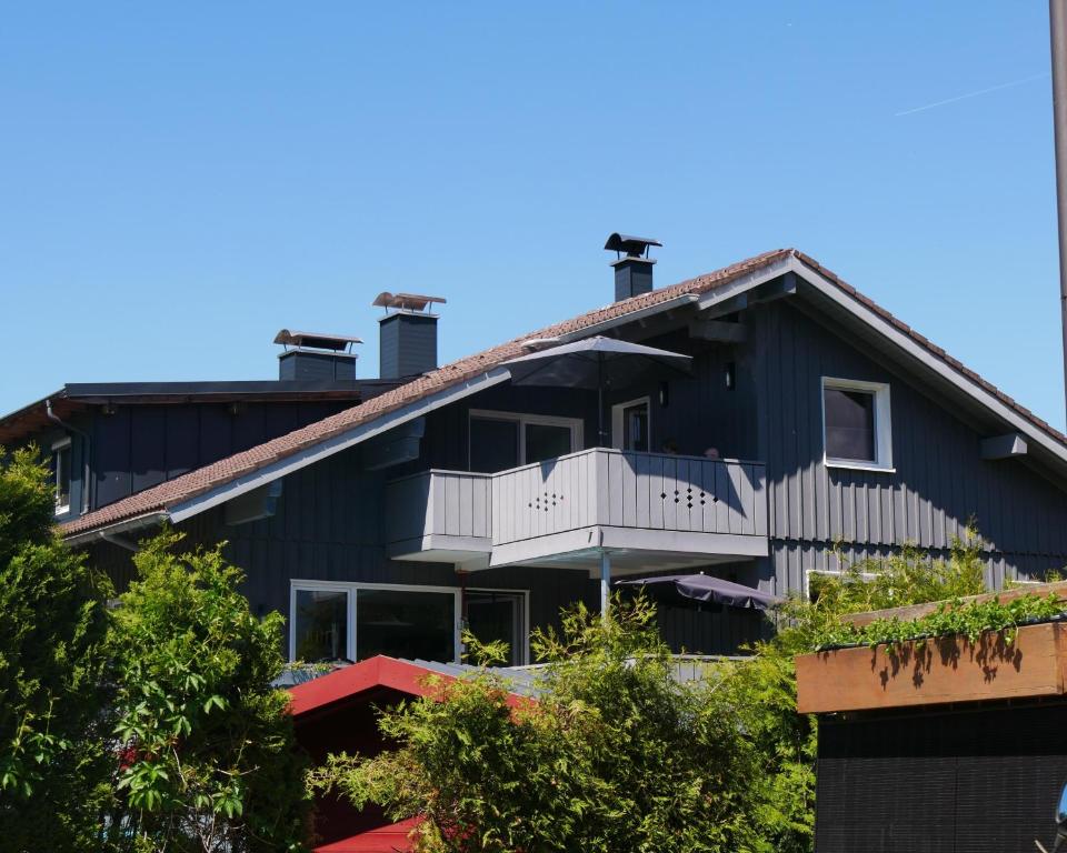 a black house with a white balcony and trees at Alpenzauber Ofterschwang in Ofterschwang
