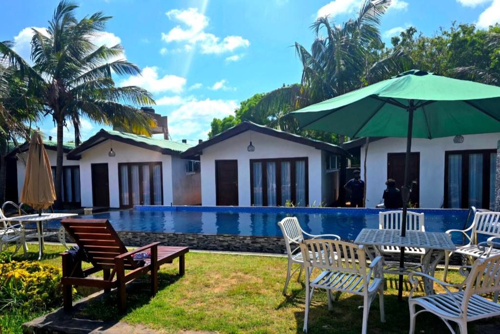 a resort with a pool and chairs and an umbrella at Beach 365 in Nilaveli
