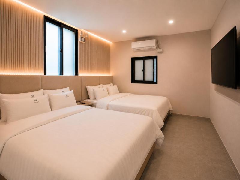 a hotel room with two beds and a flat screen tv at Busan Station Iruda Hotel in Busan