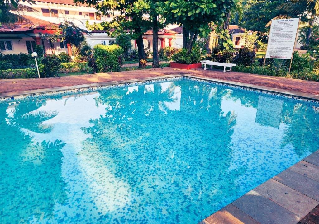 a large blue swimming pool with a bench in it at Beach villa South Goa in Arossim-Cansaulim