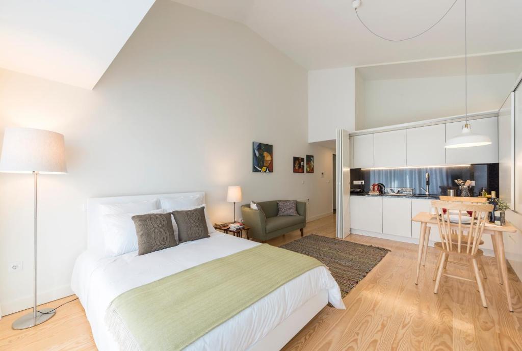 a bedroom with a large bed and a kitchen at Bright Downtown Apartment in Porto
