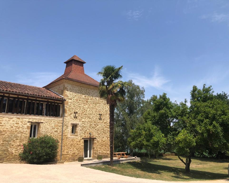 a building with a palm tree in front of it at Pigeonnier La Carole 35m2 in Monlezun