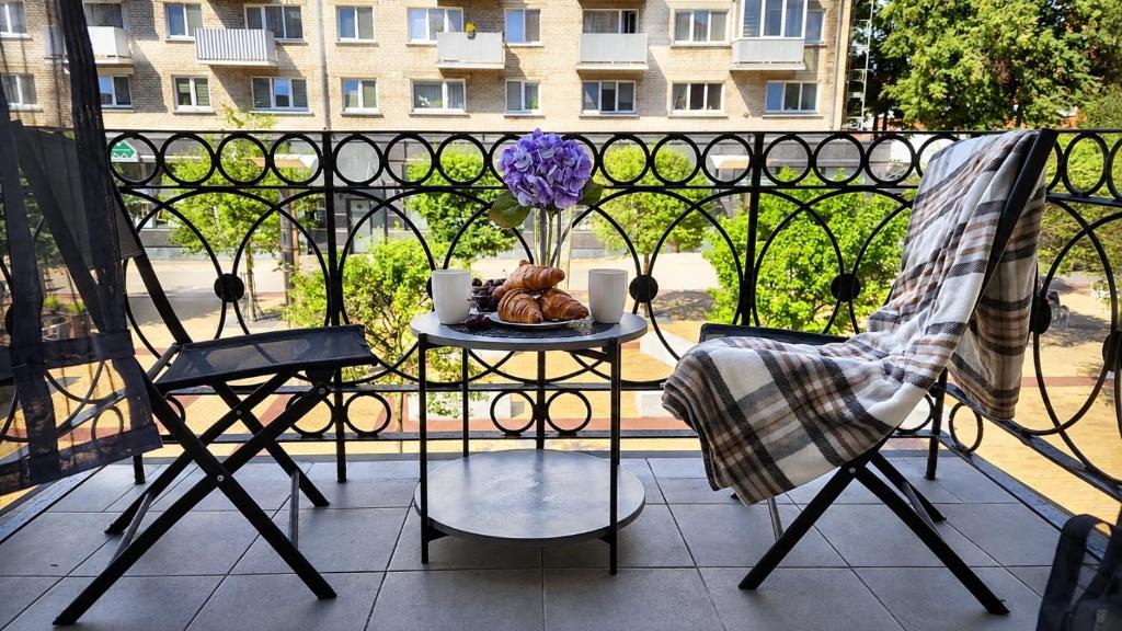 a balcony with a table with a vase of flowers at Мazvydo Avenue Studio Кlaipeda City Centre in Klaipėda