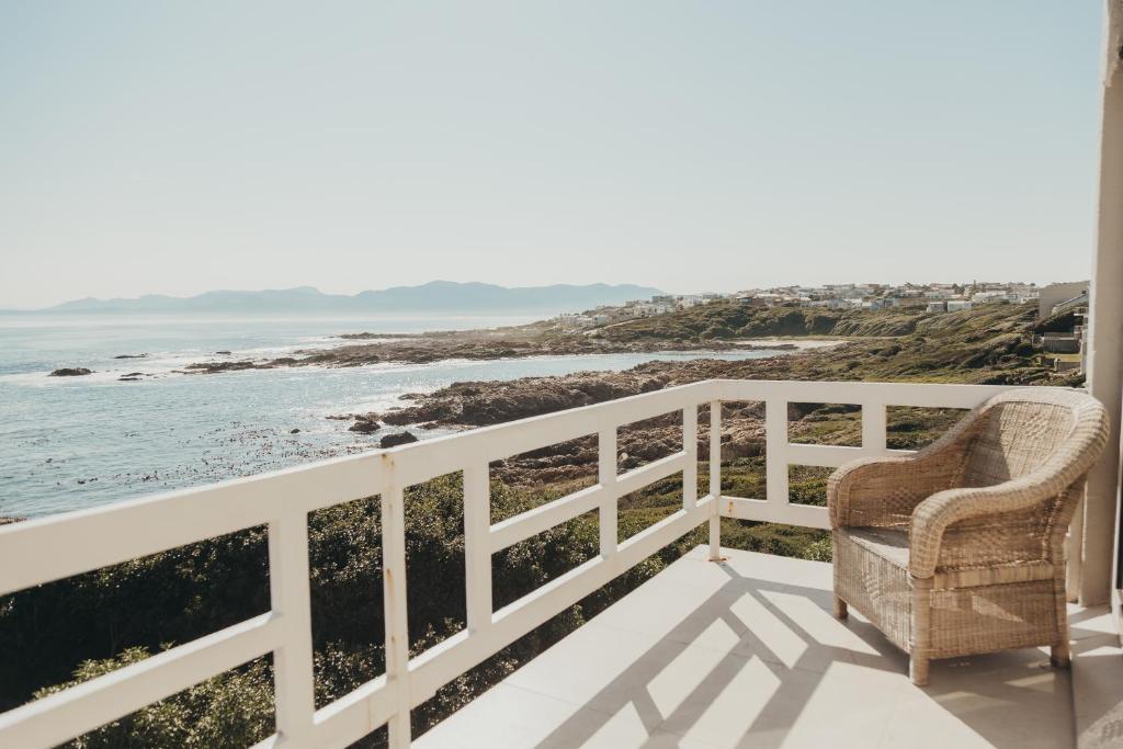 a chair on a balcony looking out at the ocean at La Melamire On the Rocks Bed & Breakfast in Gansbaai
